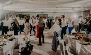 Goście bawią się na parkiecie podczas wesela za 5 tysięcy. W tle widać parę młodą i zespół muzyczny.