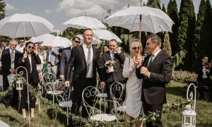 Goście weselni z parasolami czekają na ceremonię. Wiosenny ślub w kwietniu, mimo słońca, wymagał ochrony przed ewentualnym deszczem.
