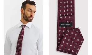 Mężczyzna w białej koszuli prezentuje bordowy krawat w białe wzory. Jego szerokość jest idealna do eleganckich stylizacji.