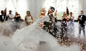 Para młoda wiruje w chmurze motyli podczas pierwszego tańca. Goście filmują i klaszczą.