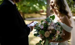 Para młoda podczas romantycznej przysięgi małżeńskiej. Ona trzyma bukiet, on czyta z kartki.