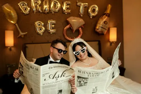Przywitanie pana młodego w domu młodej. Para w okularach czyta gazetę "The Wedding Post" z nagłówkiem "Miłość".