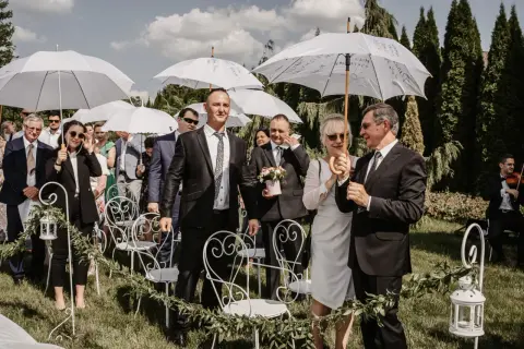 Goście weselni z parasolami czekają na ceremonię. Wiosenny ślub w kwietniu, mimo słońca, wymagał ochrony przed ewentualnym deszczem.