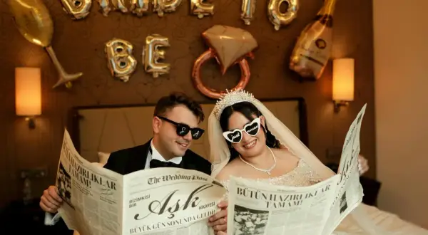 Przywitanie pana młodego w domu młodej. Para w okularach czyta gazetę "The Wedding Post" z nagłówkiem "Miłość".