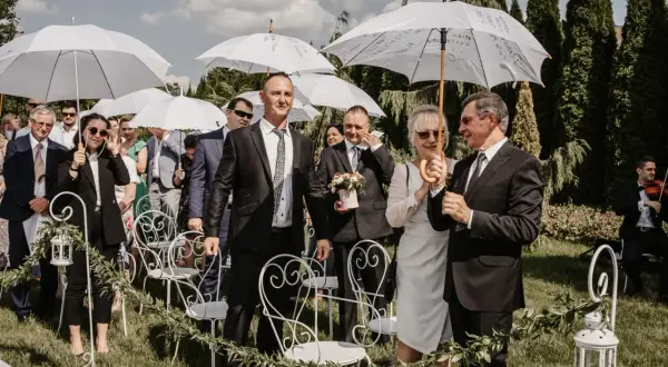 Goście weselni z parasolami czekają na ceremonię. Wiosenny ślub w kwietniu, mimo słońca, wymagał ochrony przed ewentualnym deszczem.