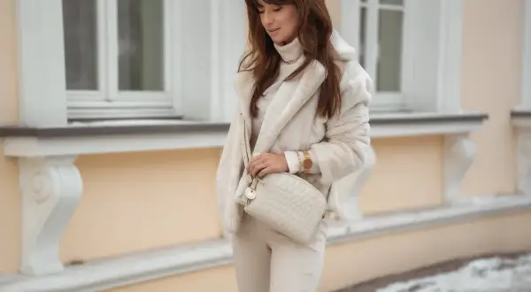 Kobieta w płaszczu i spodniach w kolorze warm beige jaki to kolor. Elegancka stylizacja w odcieniach kremu i beżu.