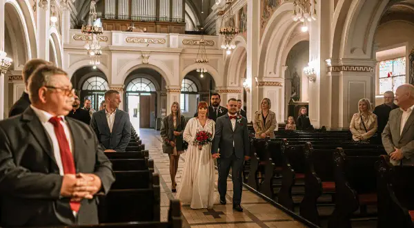 Para młoda idzie do wyjścia z kościoła, a goście śpiewają pieśń na wyjście z kościoła - ślub.