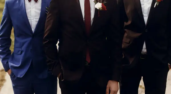 Elegancki garnitur dla niskiego mężczyzny, idealnie dopasowany, z butonierką.