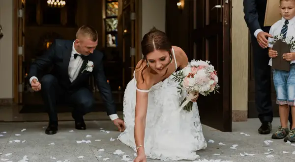 Panna młoda i pan młody zbierają monety rozsypane przed kościołem. To piękna pieśń na wejście do kościoła ślub.