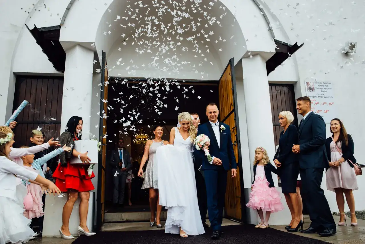 Młoda para wychodzi z kościoła, obsypana płatkami w kształcie motyli. To piękny moment, który często towarzyszy tradycji oczepin.