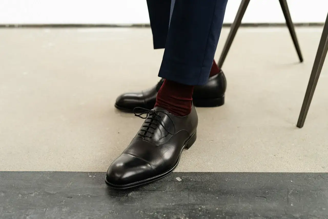 Eleganckie, czarne oksfordy z bordowymi skarpetkami – idealne buty do garnituru.
