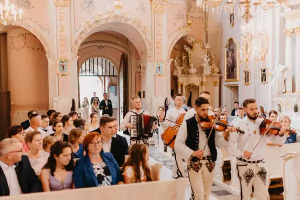 Muzycy grają pieśni na ofiarowanie ślub w kościele. W tle para młoda idzie do ołtarza.